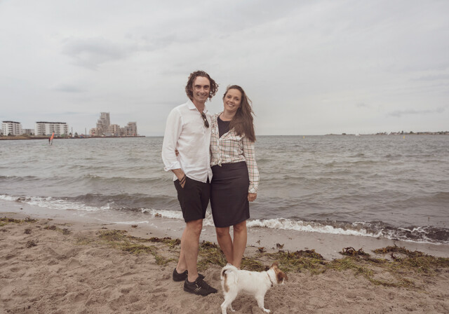 Ungt par med hund på stranden
